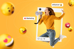 Mulher pula sorridente em frente a uma parede lisa amarelada onde está cercada por um frame do Instagram com emojis flutuantes